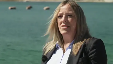 A person with long fair hair wearing a blazer and shirt