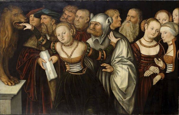 A woman sticking her hand into the mouth of a statue of a lion, surrounded by men.
