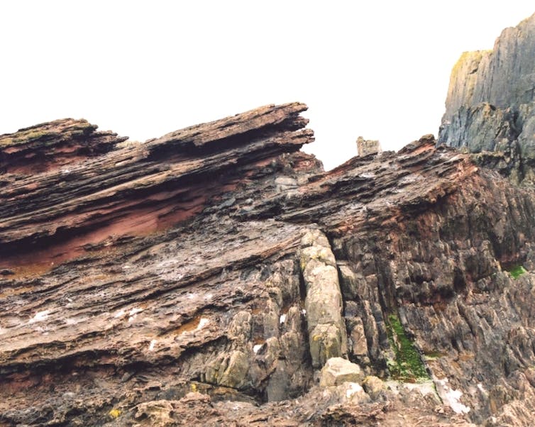 A rock formation with two layers of rocks in contrasting directions.