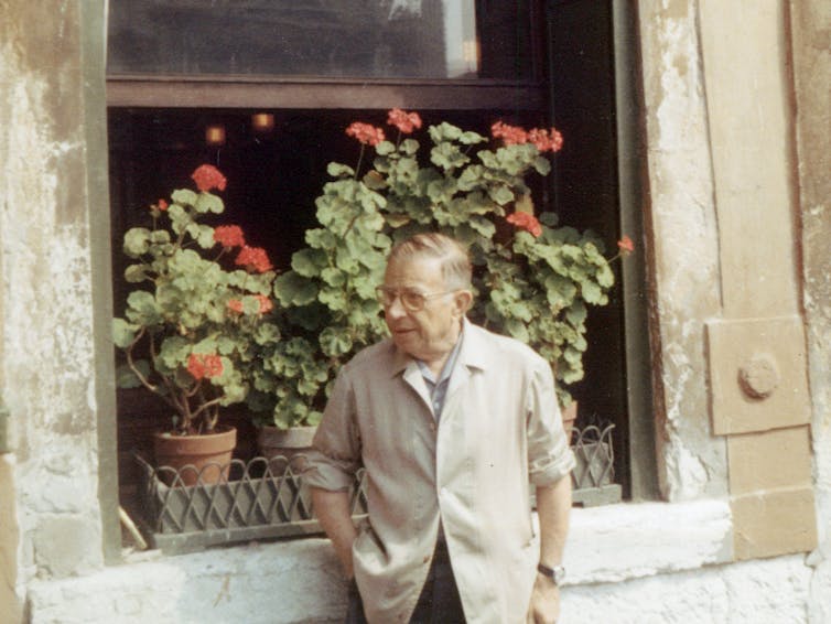 Jean-Paul Sartre in front of a window full of flowers