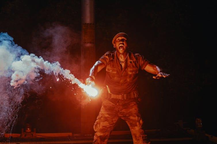 Mahershala Ali holding a red flare.