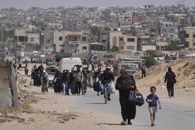 Palestinian men, women and children walking along a road in Gaza.