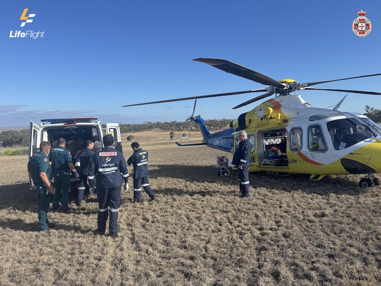 an ambulance and helicopter with paramedics on dusty earth