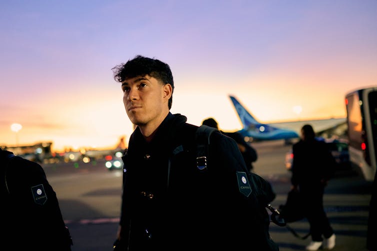 A young man looks up as he prepares to board a plane on the tarmac in Milan, Italy, for a flight to Rome on Dec. 15, 2024.