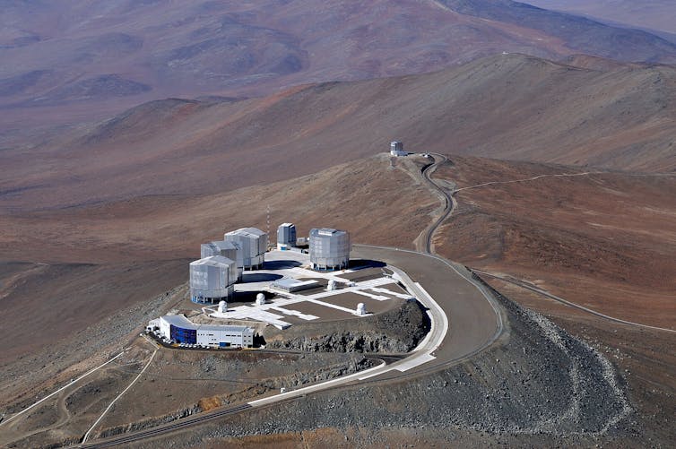 A set of buildings atop a mountain in the desert.