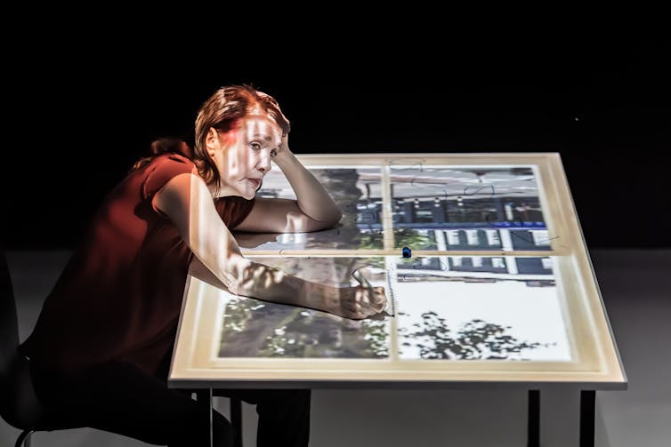 Woman sits at a desk, head in hands