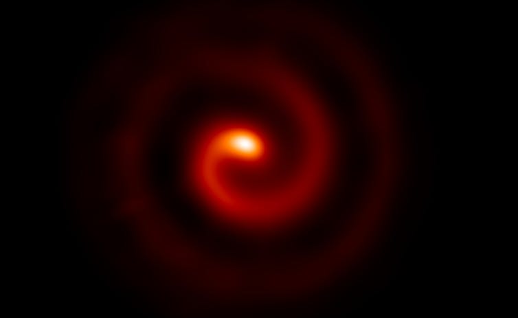 A black backfground with a swirling red spiral in the centre that brightens to an orange globe.