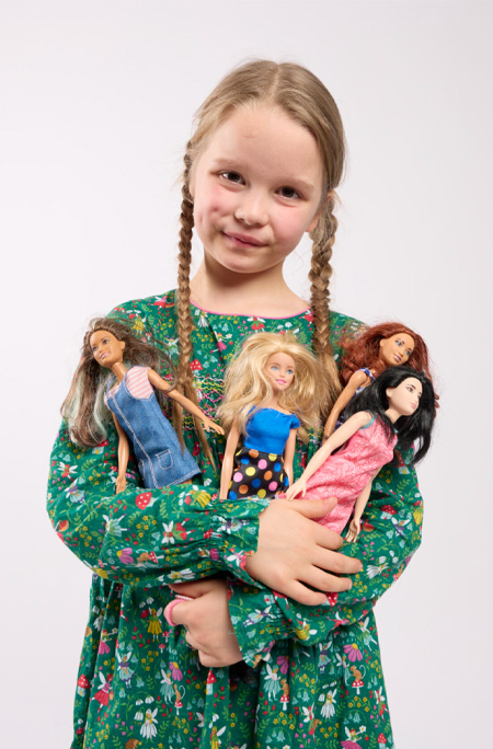 Girl holding four Barbies