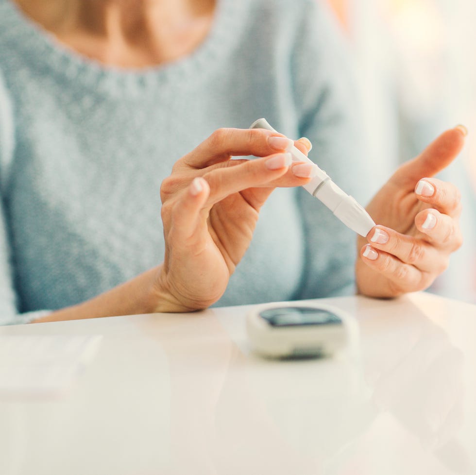 mature woman doing blood sugar test at home.