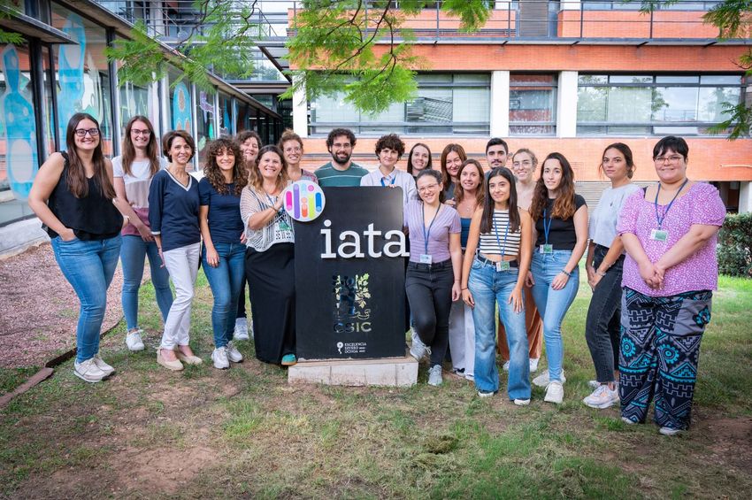 A group of laboratory researchers stand outside on the grass.