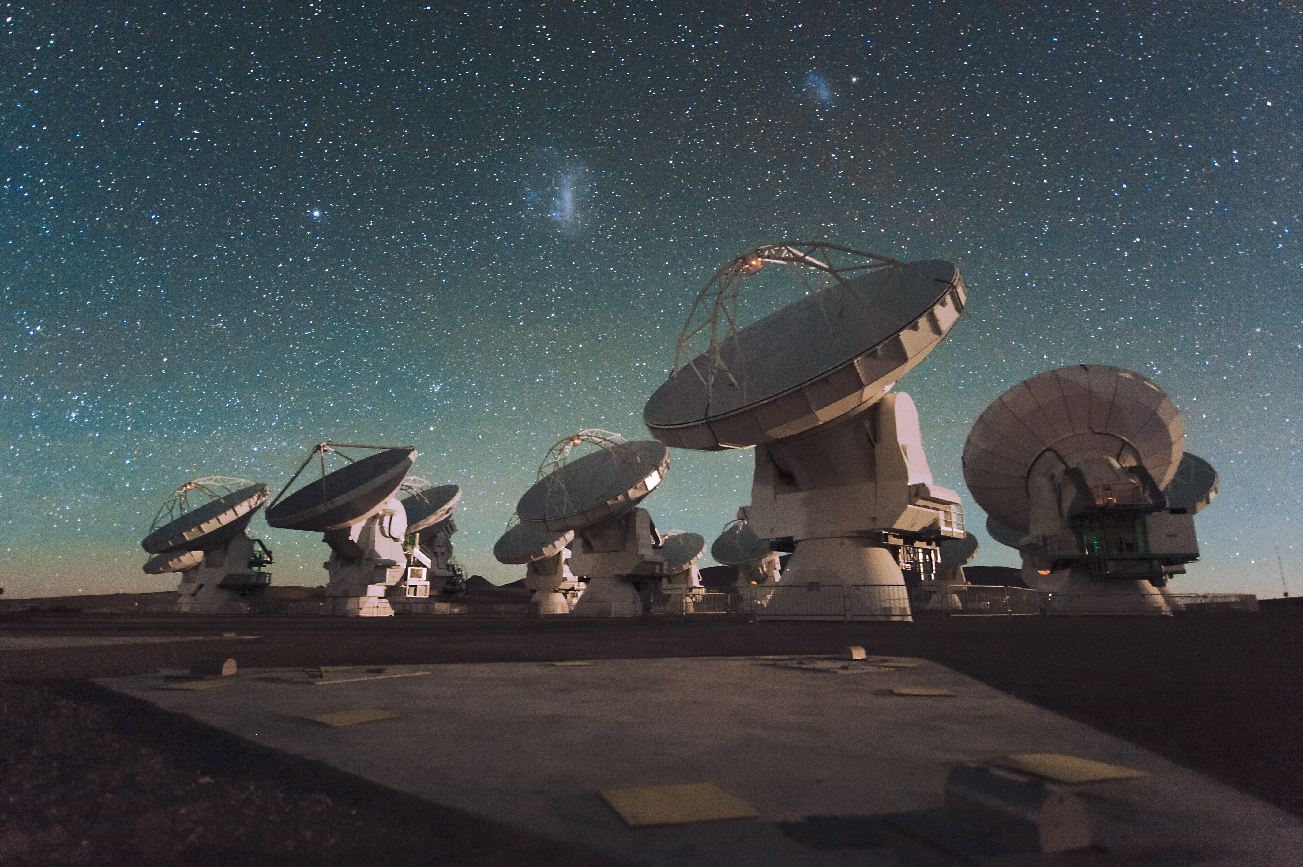 a dozen or so of the antennas in the ALMA radio telescope array, shown beneath a dark, starry sky