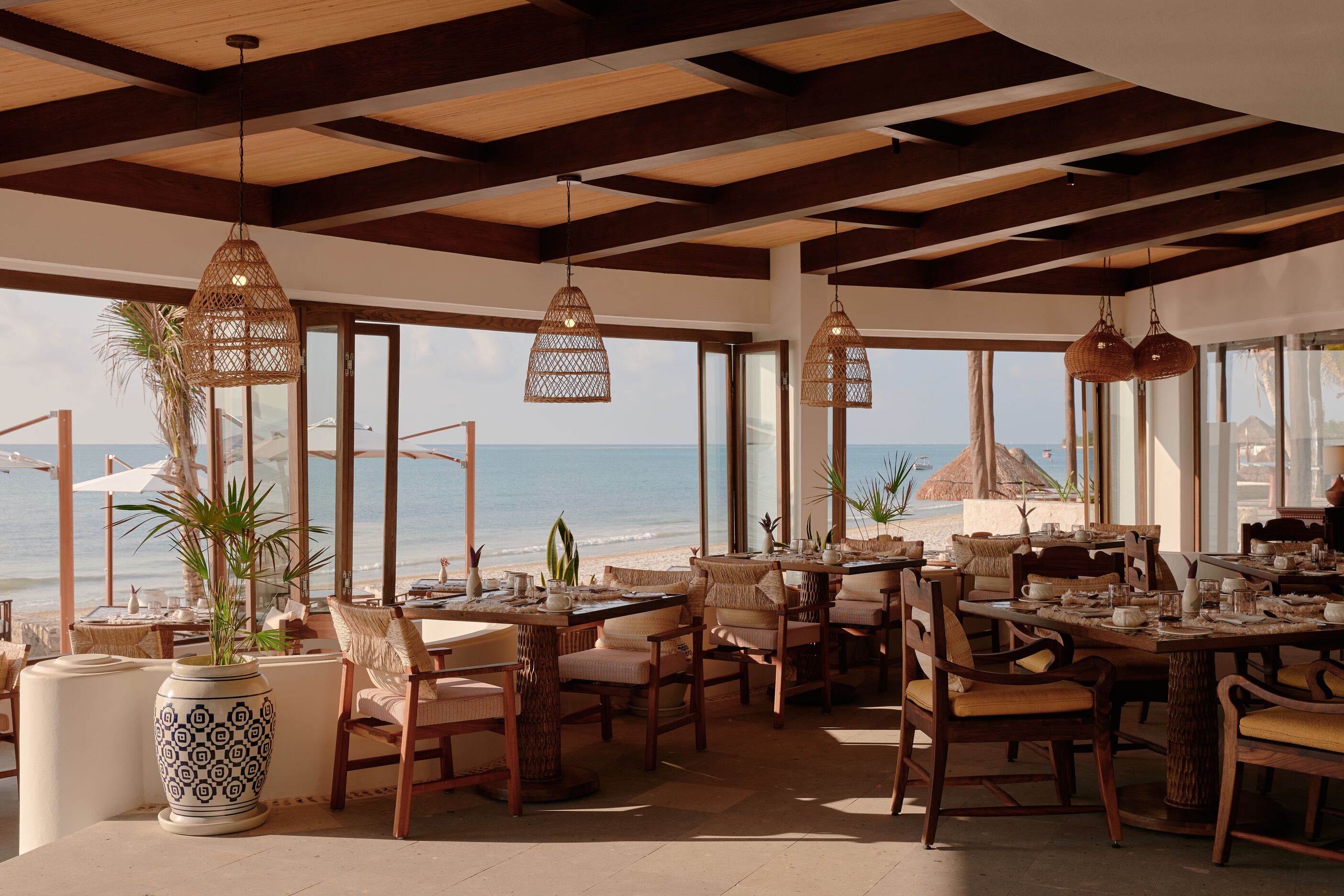 Oceanfront restaurant with wooden tables and chairs.