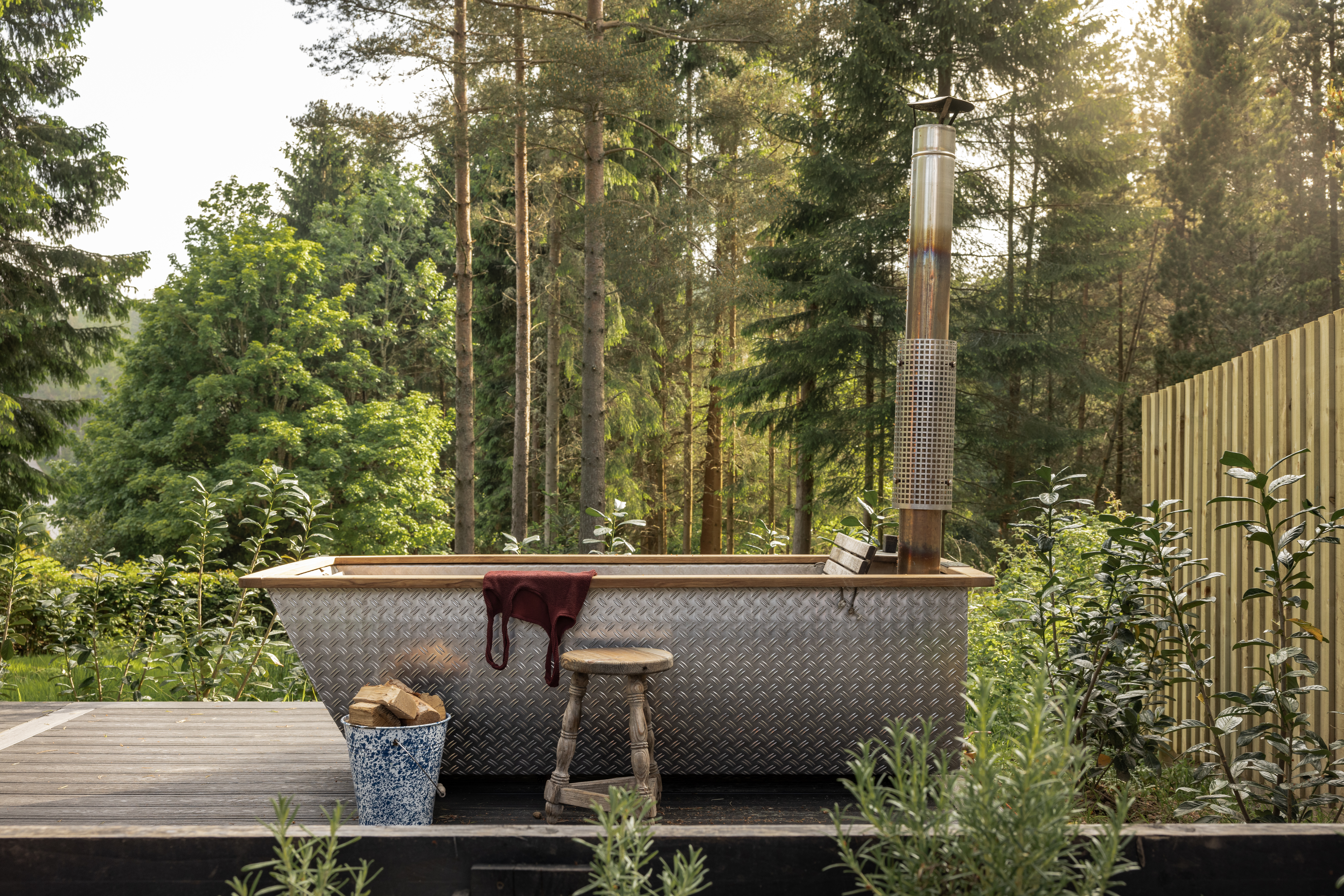 Outdoor wood-fired hot tub in a forest setting.