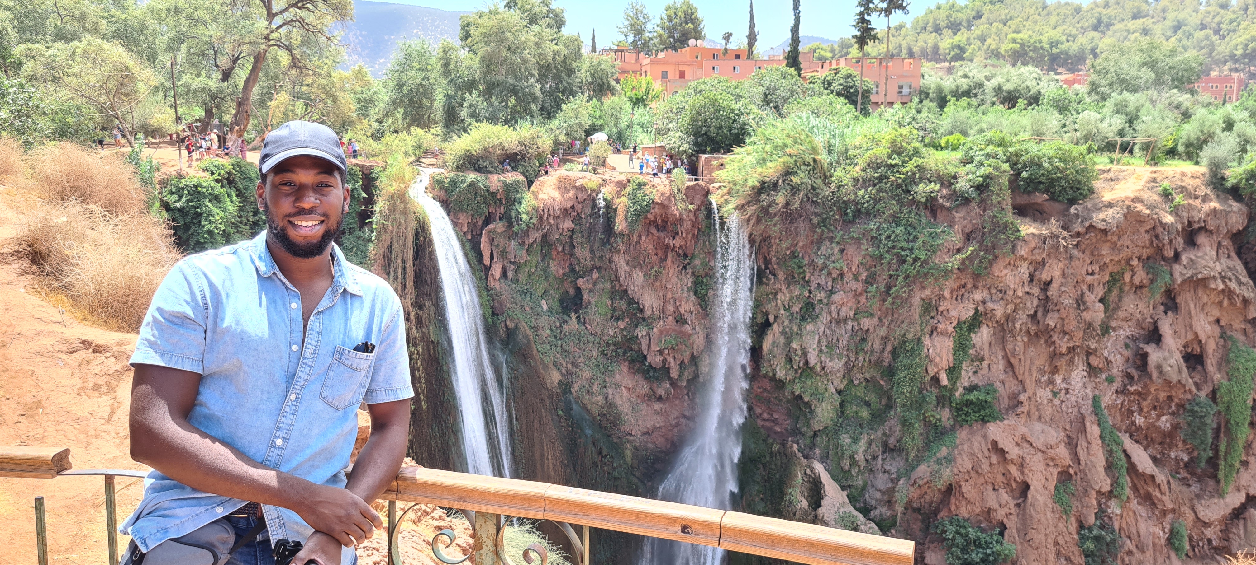 Man smiling in front of a waterfall.