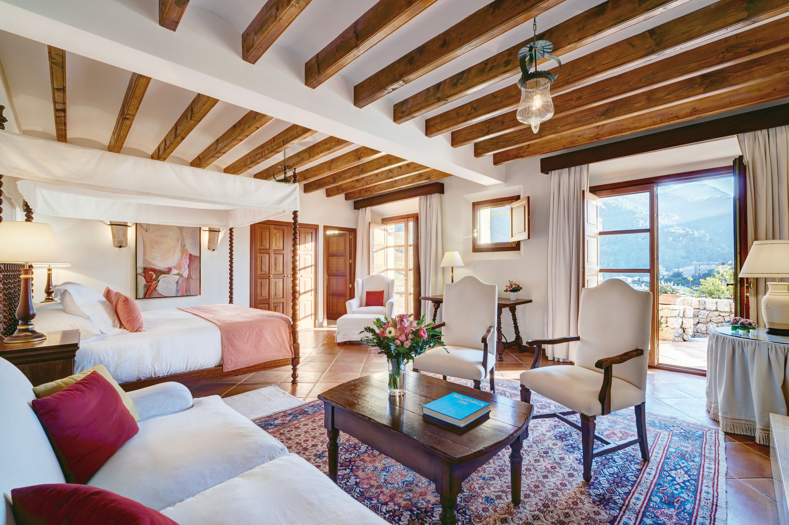 Hotel suite with four-poster bed and mountain view.