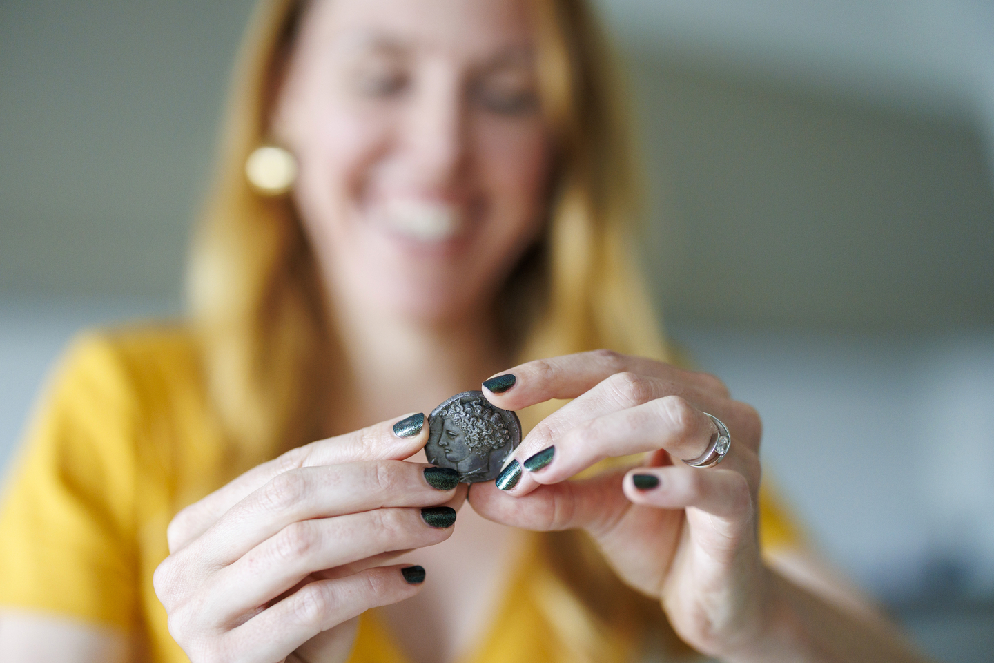 Laure Marest holds an ancient Greek coin.