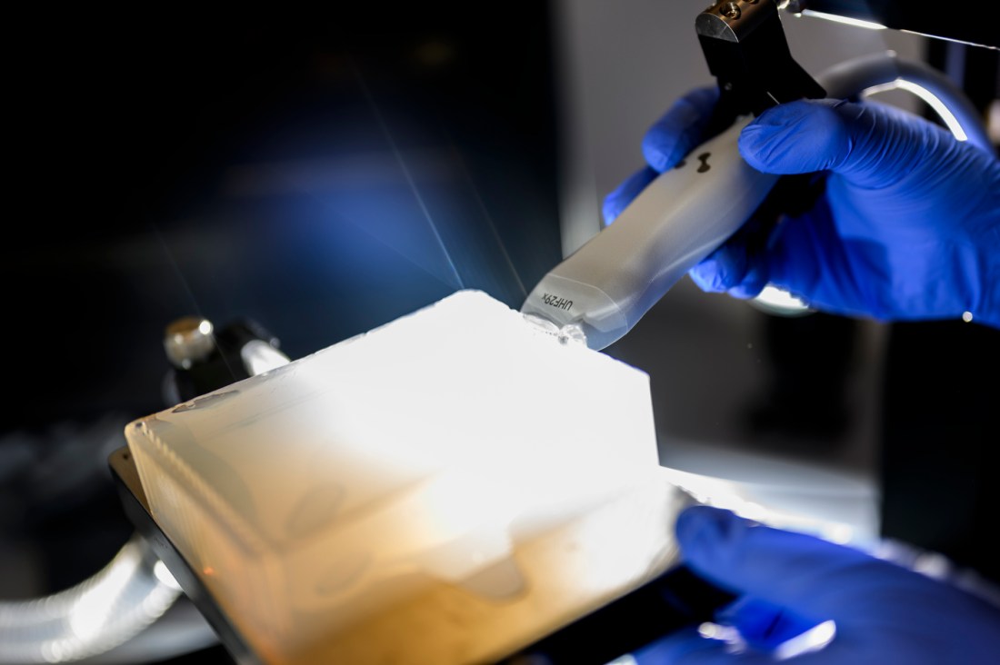 Tao Sun's gloved hands operating ultrasound research equipment.