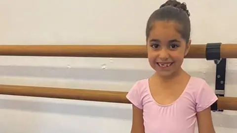 Family handout Alice with her brown hair in a bun dressed in a pink leotard in a dance studio. She is smiling.