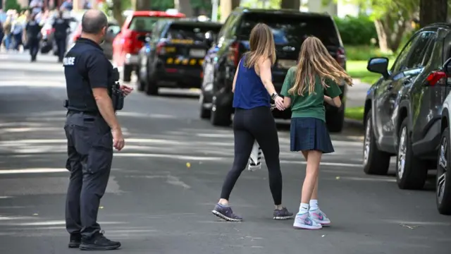 An adult and child comfort each other as the leave the school as police respond to a shooting at the Annunciation Catholic School in Minneapolis