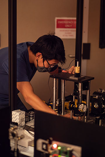 Researcher in surgical mask working on a device