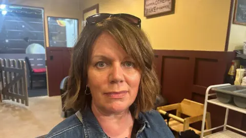 A woman with short brown hair with sunglasses on her head