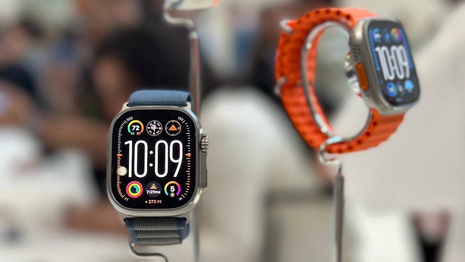 Two Apple Watch Ultra 2 models, propped up on a demo table. Blurred background.