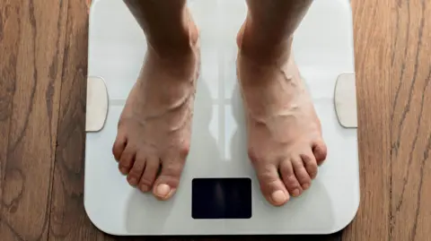 Getty The feet of a person standing on bathroom scales 