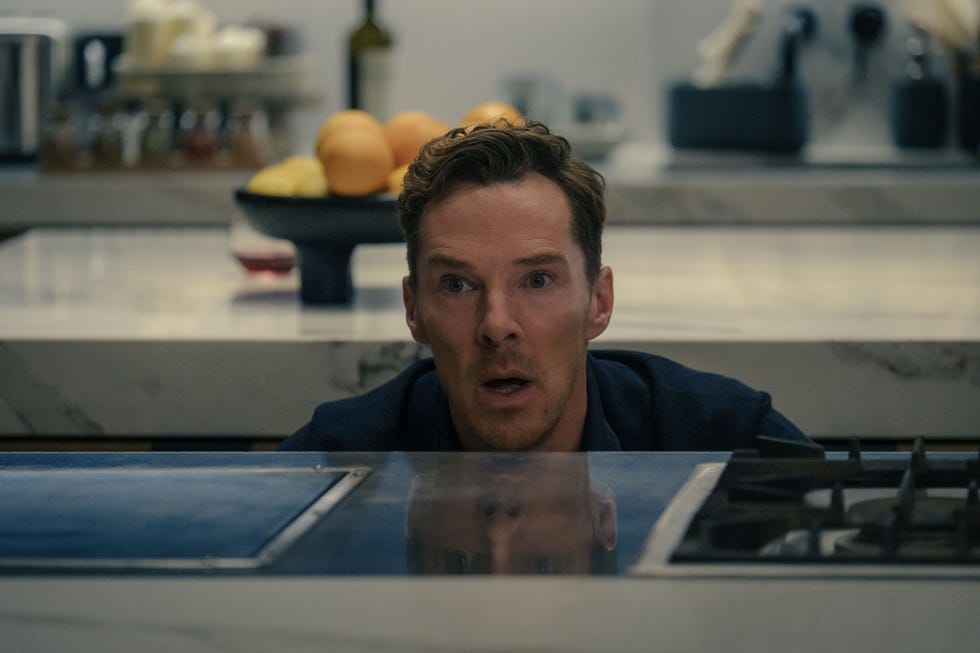 Person at the kitchen counter with a stove and various kitchen objects in the background.
