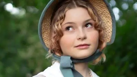 Ben Simkins Theia looks off into the distance, wearing a blue trimmed bonnet and a white dress. She has blonde hair and brown eyes and is wearing subtle make-up.