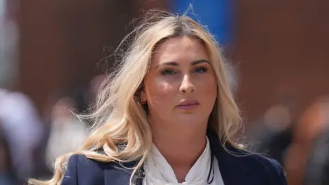 PA Media Nikita Hand, a woman with long blonde hair, wearing a navy blazer and white blouse. 