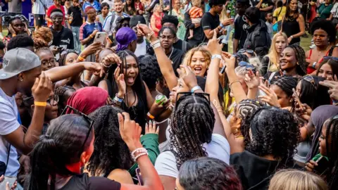 Mary Doggett/Afri-Fest East A big group of happy festival goers with arms in the air dancing to music.