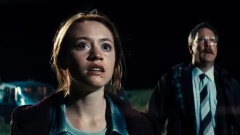 XYZ Films A still from the movie Watch the Skies where a young woman and a man stare into the night sky.