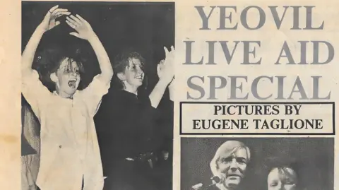 Yeovil Mail A newspaper clipping of the Live Aid fundraiser in Yeovil. The headline is "Yeovil Live Aid Special". Underneath is "pictures by Eugene Taglione" and below that a picture of a man and a woman. To their left is a picture of two woman dancing, one jumping with her hands in the air and the other is clapping and smiling.