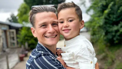 Supplied by family Tom is holding is son Jenson in his arms, their faces are touching and they are both smiling at the camera.