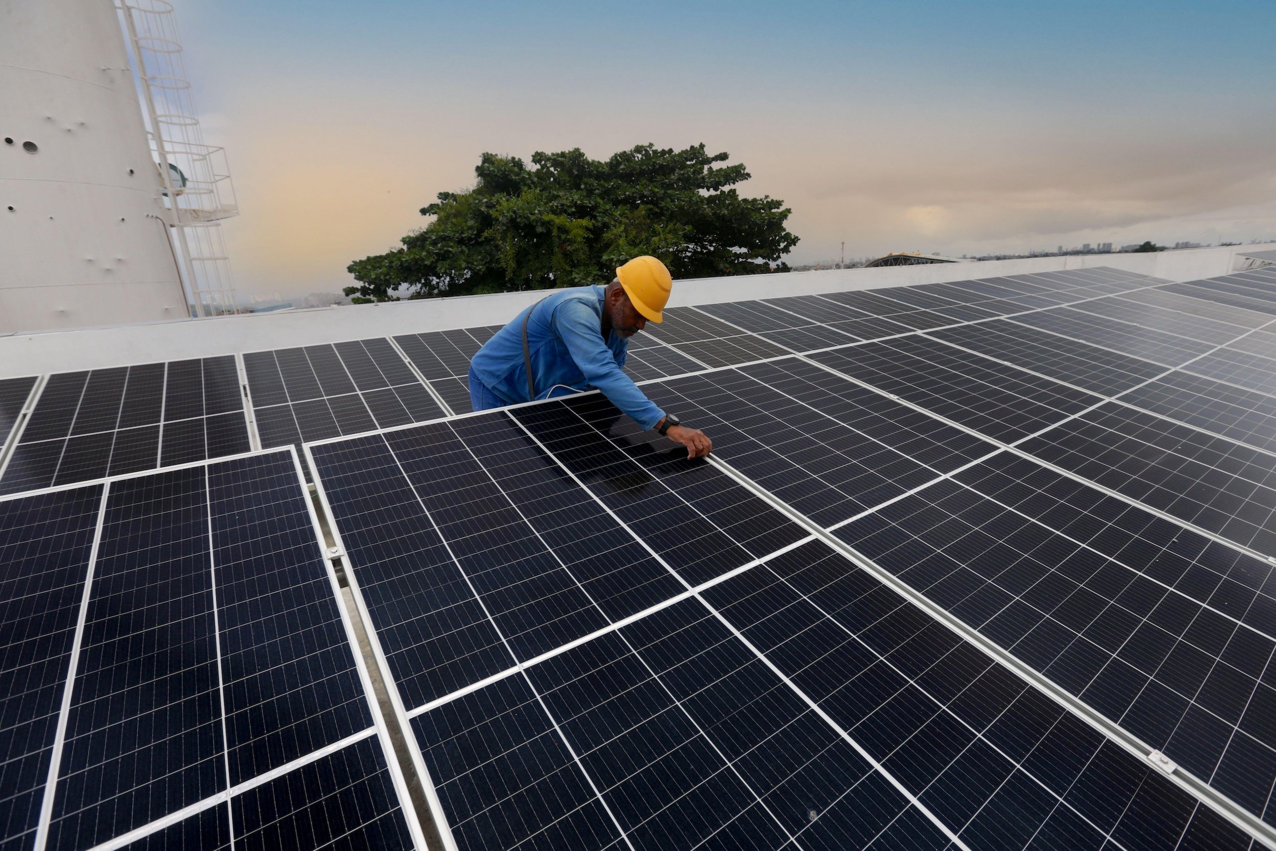 A worker installs solar energy panels on the roof of a building