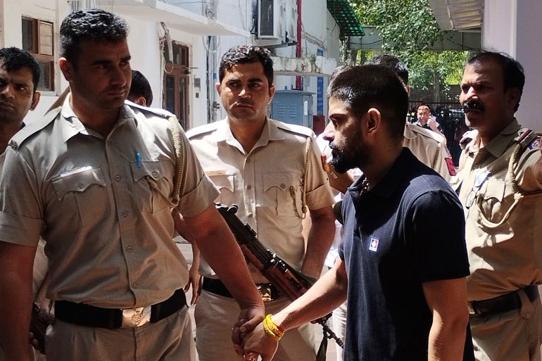 Policemen escort jailed gangster Lawrence Bishnoi as they bring him to produce before the Patiala House court in New Delhi, India, Tuesday, April 18, 2023. (AP Photo/Dinesh Joshi)