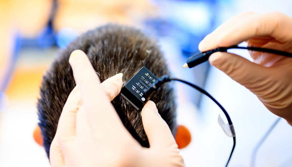 A clinical research coordinator connects a neural data port in Ann Johnson's head