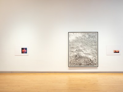 Three framed artworks on a white museum wall.