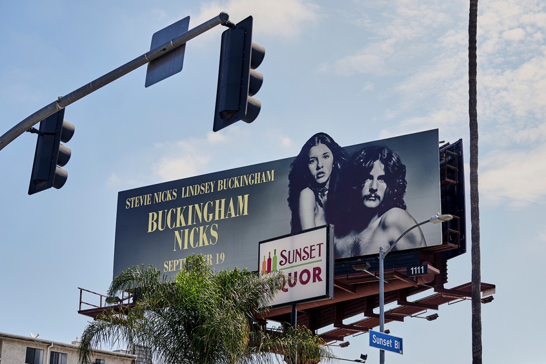 A billboard sign depicting Stevie Nicks and Lindsey Buckingham.