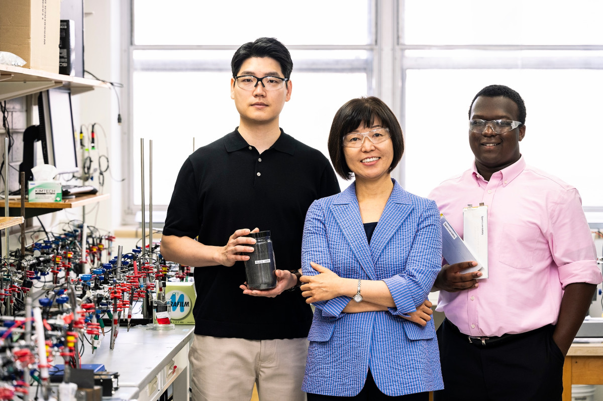 Three people stand together for a portrait in a chemistry lab.