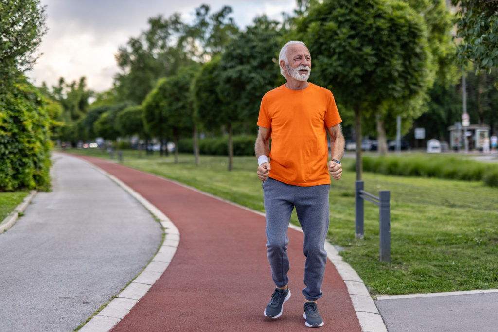 Senior man jogging in a public park maintaining a healthy lifestyle