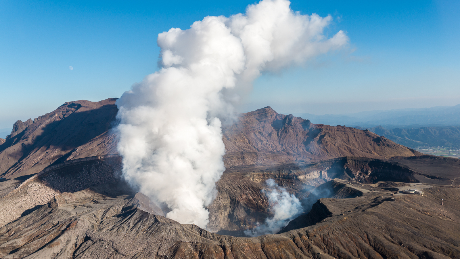 A photo of steam rising from a vent on the side of a volcano