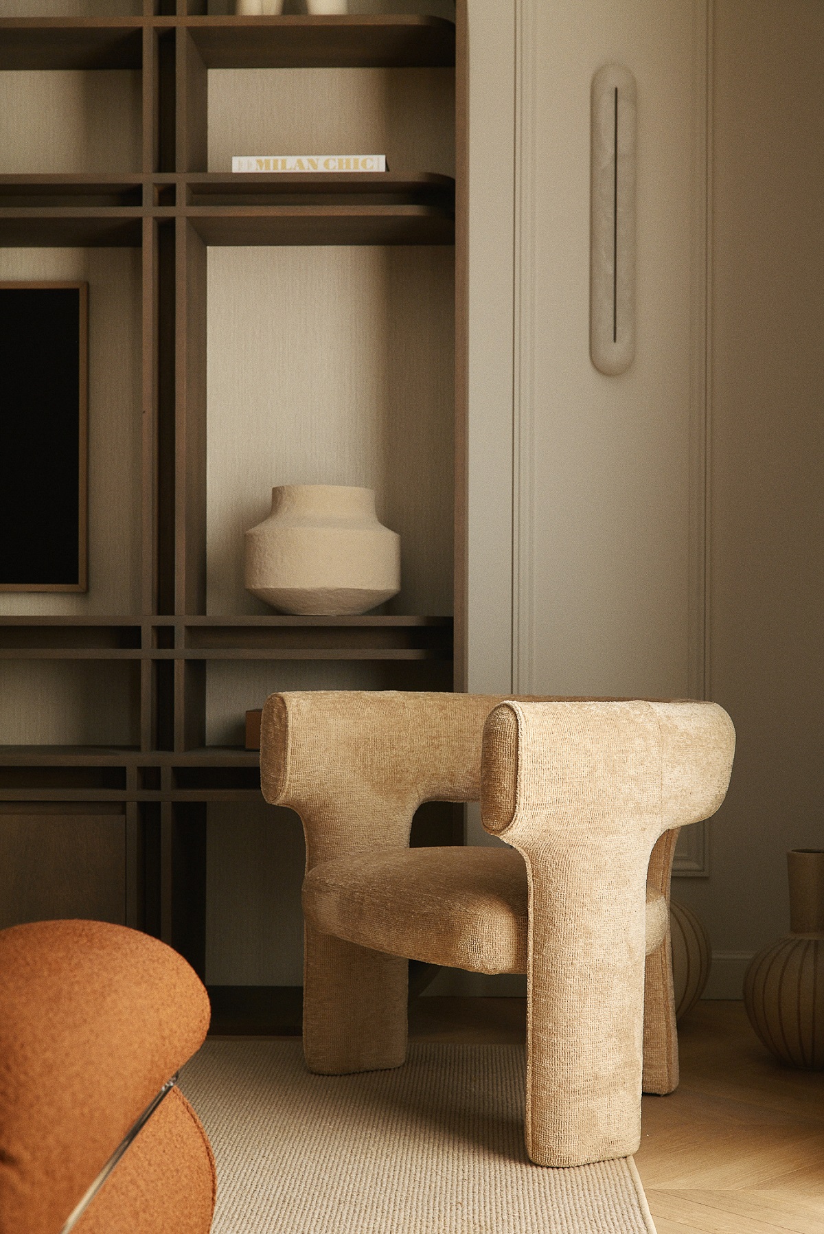 cream soft upholstered chair in front of shelving