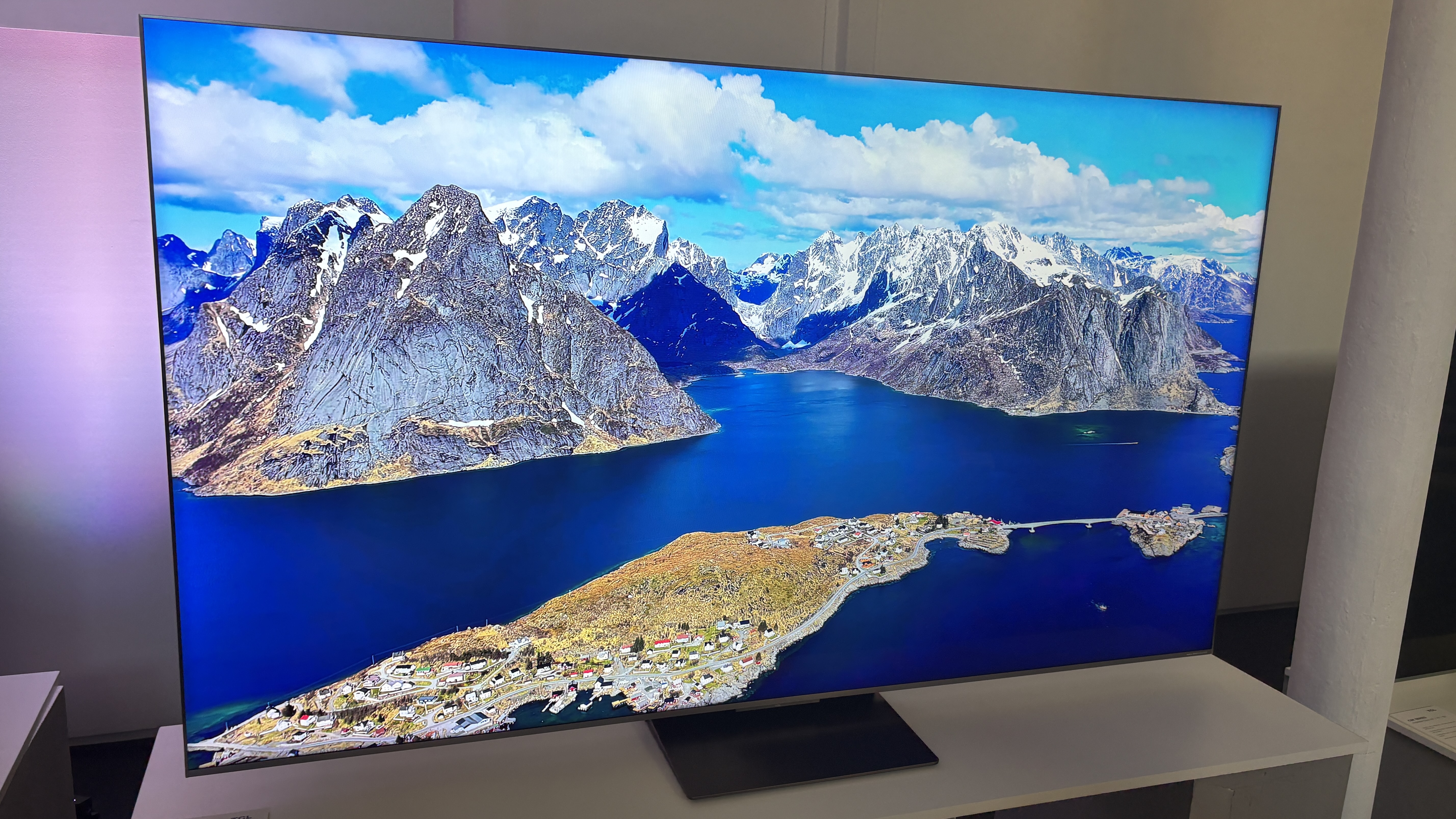 TCL C8K TV on a white media unit with nature shots on screen