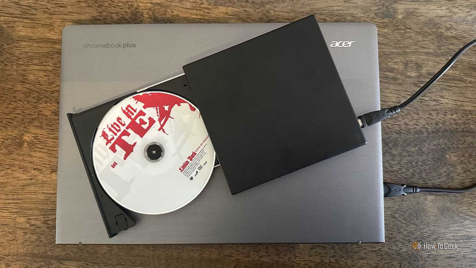 A Chromebook with a DVD drive and a Linkin Park disc on top.