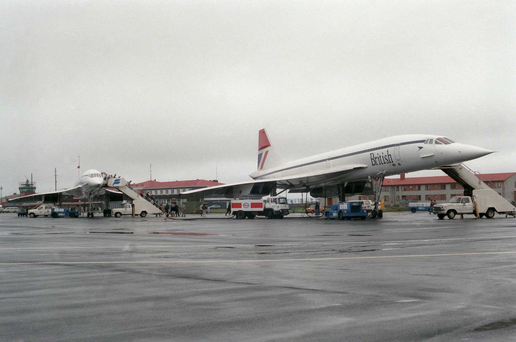 A right front view of two British Airways Concorde aircraft parked on the flight line at NAS Keflavik. The aircraft are on an around-the-world test flight