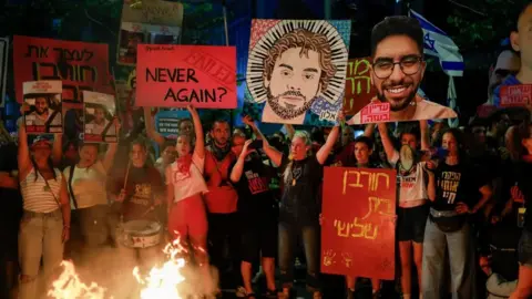 Reuters Demonstrators in Tel Aviv stand by a fire, during a protest to demand the immediate release of hostages held in Gaza