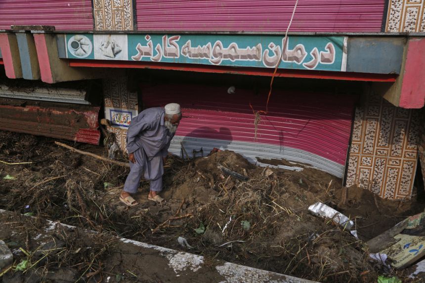 A shopkeeper removes mud and debris in front of his shop following Friday's flash flooding at a market in Pir Baba, an area of Buner district, Pakistan, on August 17, 2025.