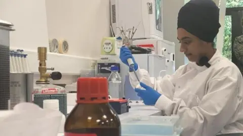 BBC A view of a researcher preparing samples to be analysed in a machine.