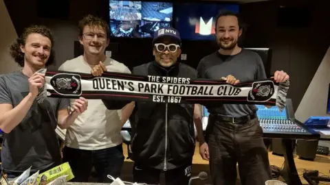 Fergus McCreadie Four men standing in a recording studio. They are holding a scarf saying Queen's Park Football Club on it.